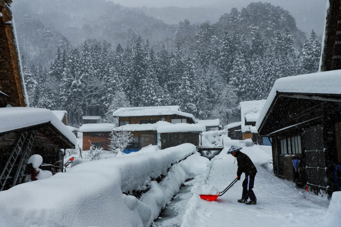 Man shovels snow Ogimachi Shirakawago Gifu Japan