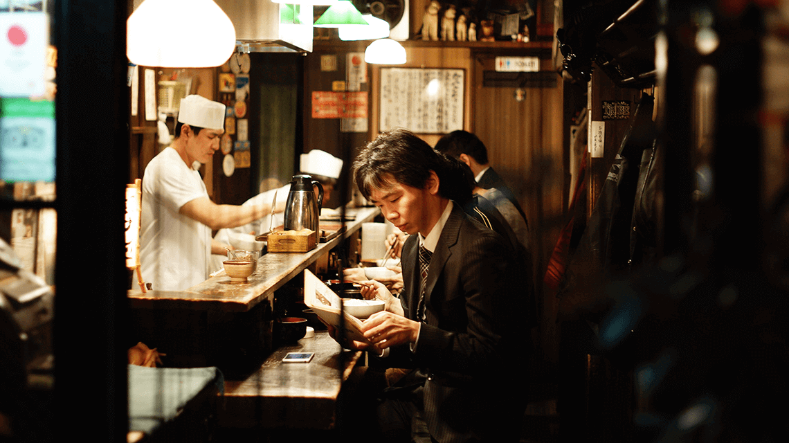 A Japanese man browses the menu in a small izakaya in Shinjuku, Tokyo, Japan