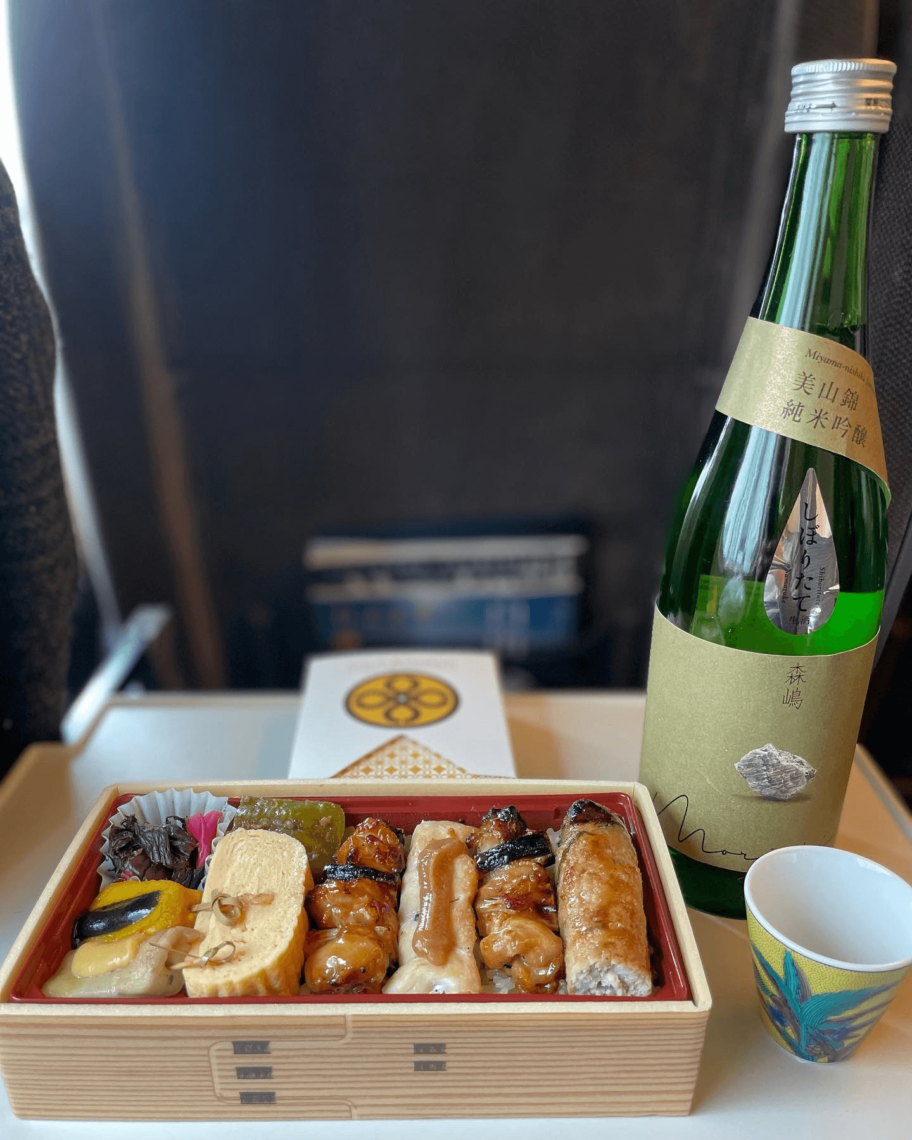 Yakitori bento with sake and tonkatsu sandwich in background on shinkansen